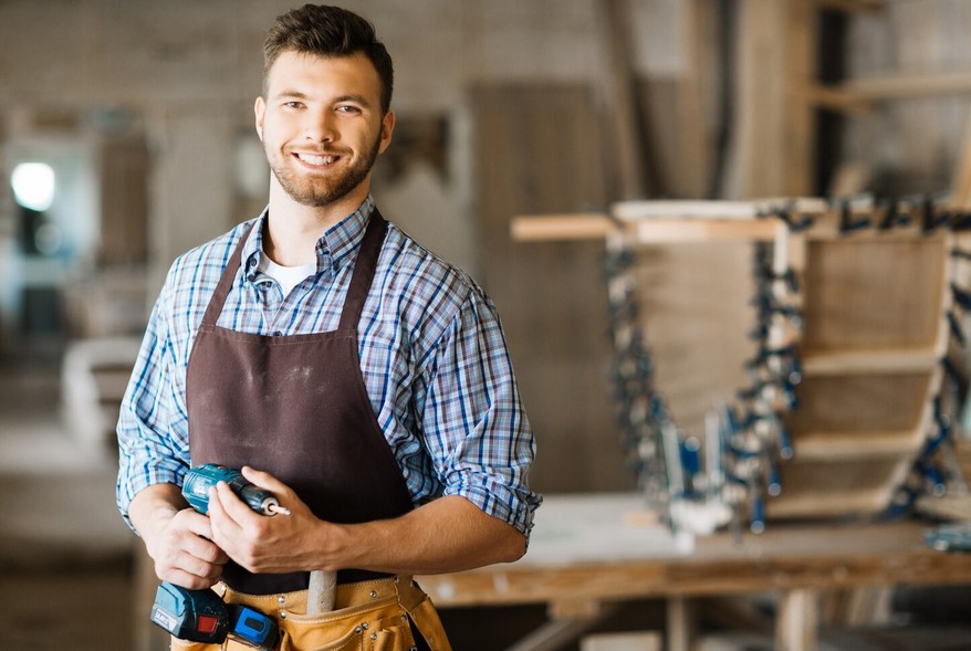 Handwerker wünschen sich Entlastung von Routinearbeiten im Büro. Foto: Magnific https://www.magnific.com/free-photo/smiling-craftsman-with-electric-drill_5401689.htm Hhandwerker_Magnific_smiling-craftsman-with-electric-drill_5401689
